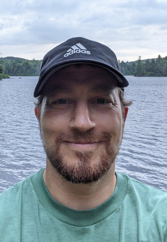 a man taking a selfie in front of a lake