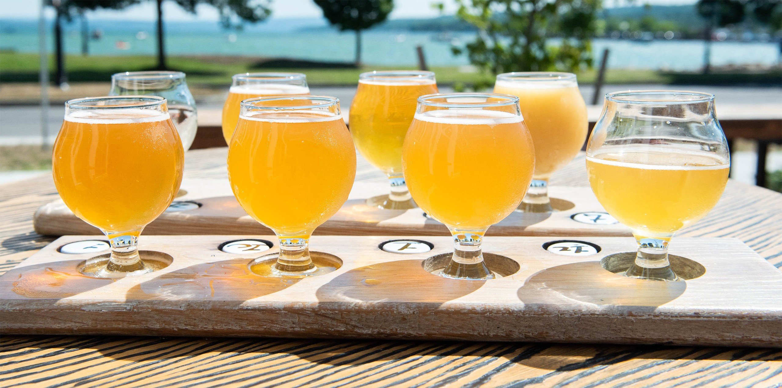 a group of glasses of beer on a wood board